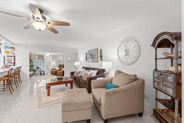 living room with ceiling fan, light tile patterned floors, and a textured ceiling