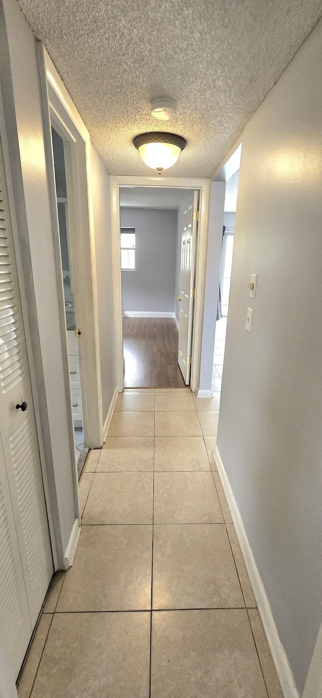 hallway featuring light tile patterned floors and a textured ceiling