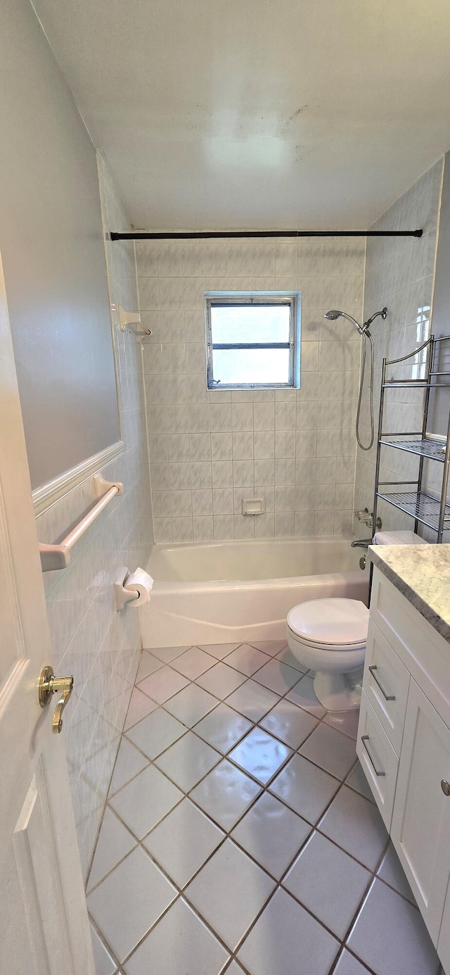 full bathroom with tile patterned floors, vanity, tiled shower / bath combo, and toilet