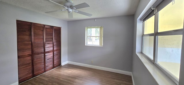 unfurnished bedroom featuring a textured ceiling, a closet, dark wood-type flooring, and ceiling fan