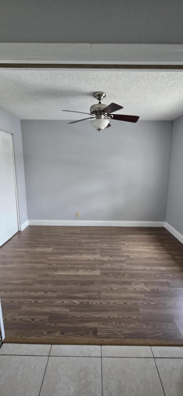 tiled empty room featuring ceiling fan and a textured ceiling