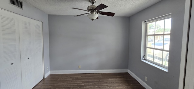 unfurnished bedroom with a closet, dark hardwood / wood-style floors, a textured ceiling, and ceiling fan