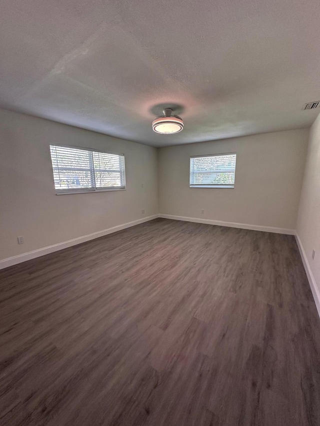 spare room featuring dark wood-type flooring and a textured ceiling