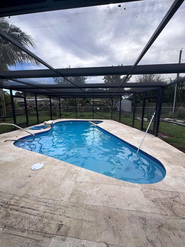 view of pool featuring glass enclosure and a patio area