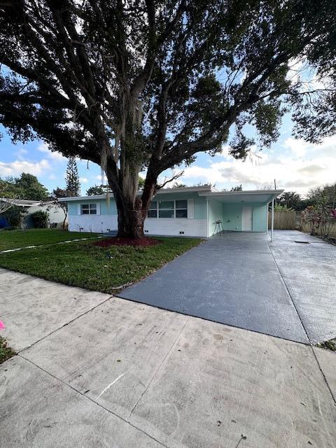 ranch-style home with a front yard and a carport