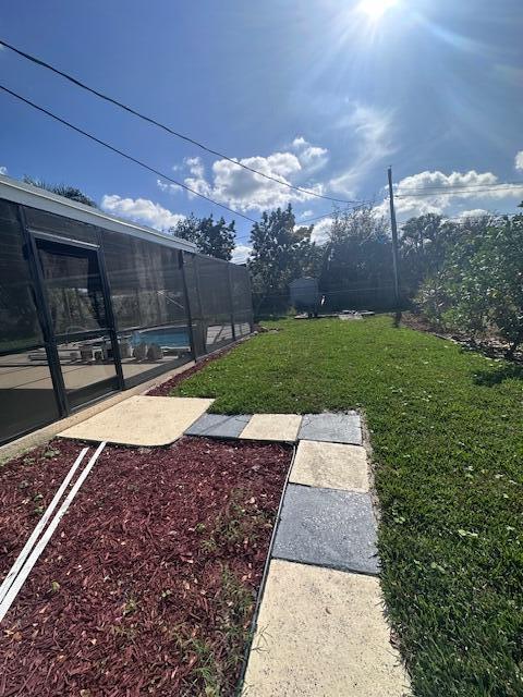 view of yard with glass enclosure and a swimming pool