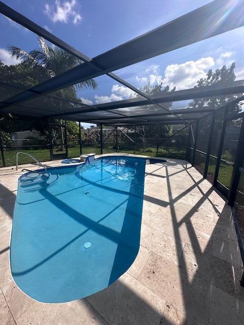 view of swimming pool with a patio and glass enclosure