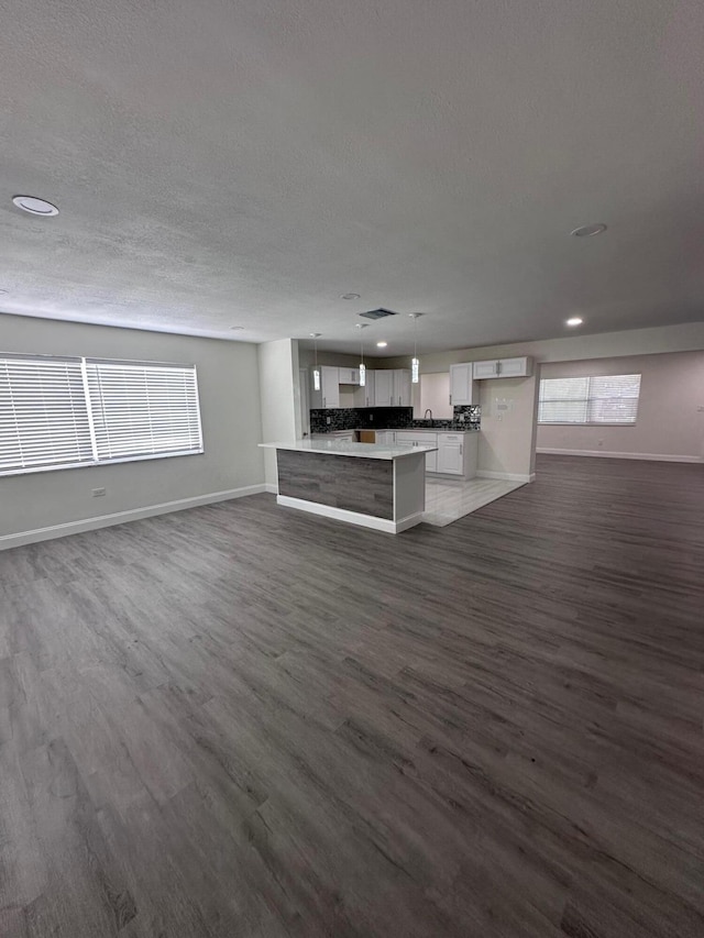 unfurnished living room featuring a textured ceiling, plenty of natural light, and dark wood-type flooring