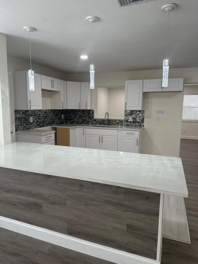 kitchen with white cabinetry, sink, and pendant lighting