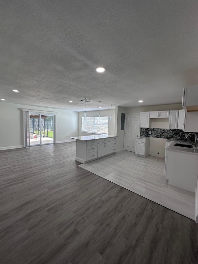 unfurnished living room featuring a textured ceiling, light wood-type flooring, and sink