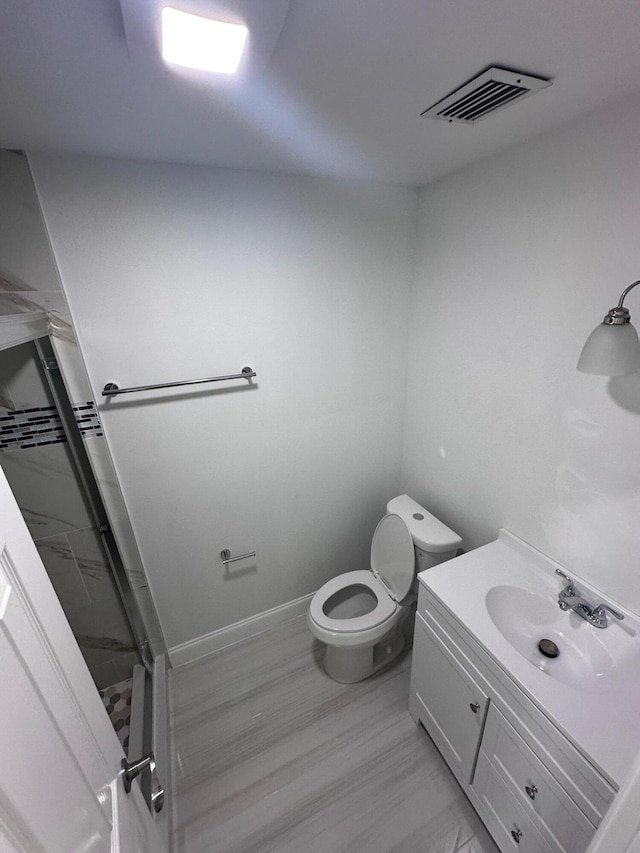 bathroom featuring vanity, toilet, wood-type flooring, and walk in shower