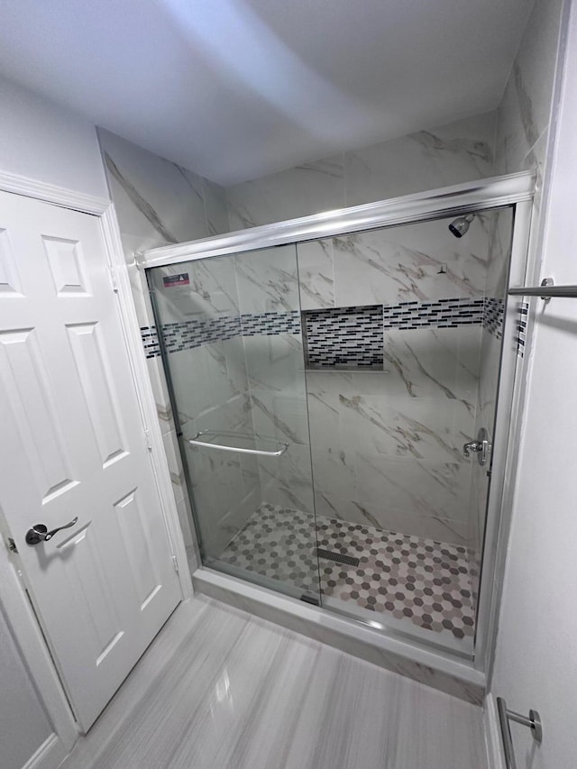 bathroom with hardwood / wood-style flooring and a shower with shower door