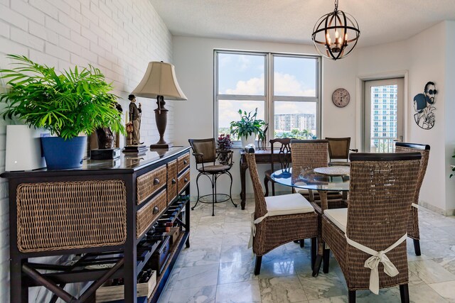 dining space featuring brick wall, a textured ceiling, and a notable chandelier