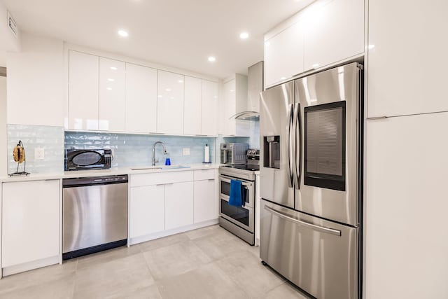 kitchen featuring tasteful backsplash, wall chimney exhaust hood, stainless steel appliances, sink, and white cabinetry