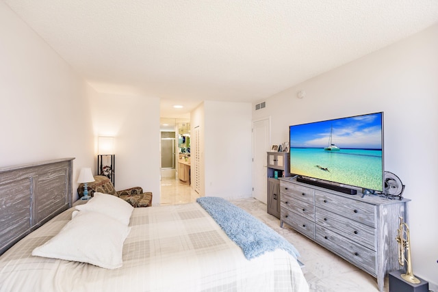 bedroom with ensuite bath and a textured ceiling