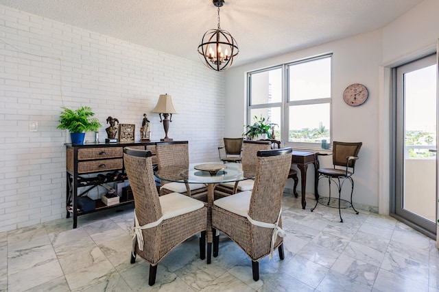 dining space with a textured ceiling, brick wall, and an inviting chandelier