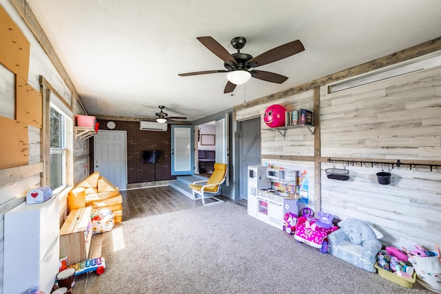 playroom featuring a wall mounted AC, wooden walls, ceiling fan, and dark colored carpet