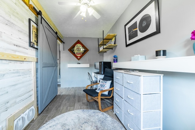 office area with a barn door, ceiling fan, and wood walls