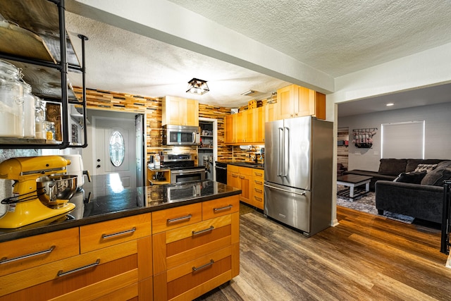 kitchen featuring decorative backsplash, appliances with stainless steel finishes, a textured ceiling, and dark hardwood / wood-style floors