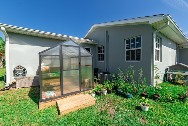 rear view of house with central AC, a yard, and an outdoor structure