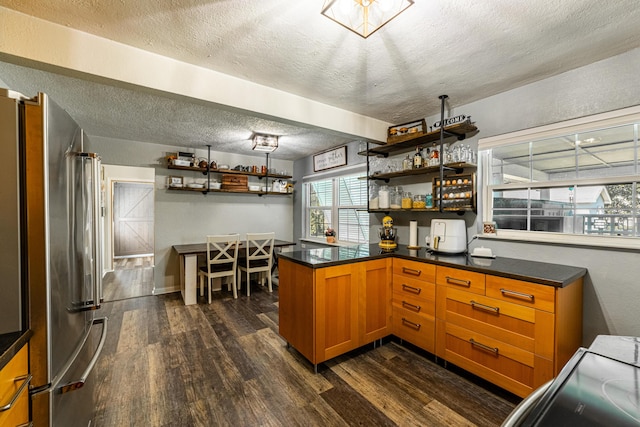 kitchen with kitchen peninsula, a textured ceiling, dark hardwood / wood-style floors, and stainless steel refrigerator