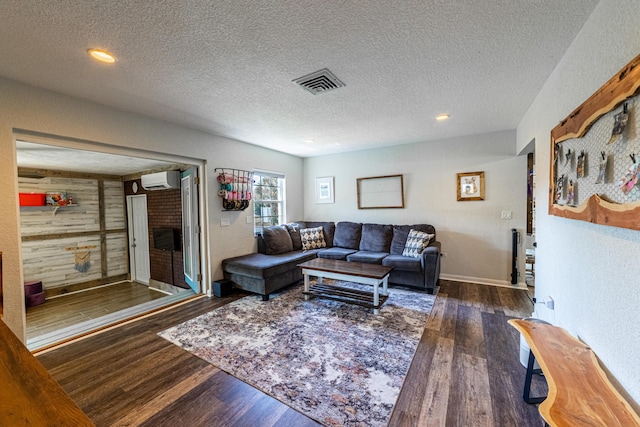 living room featuring a textured ceiling, a wall unit AC, and dark hardwood / wood-style floors