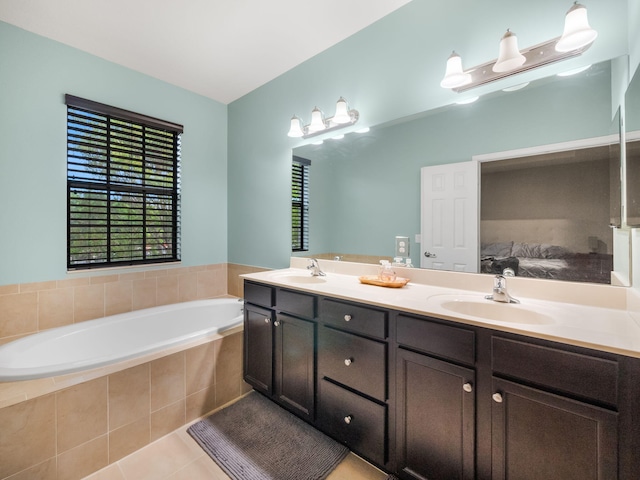 bathroom featuring tiled tub, tile patterned flooring, and vanity