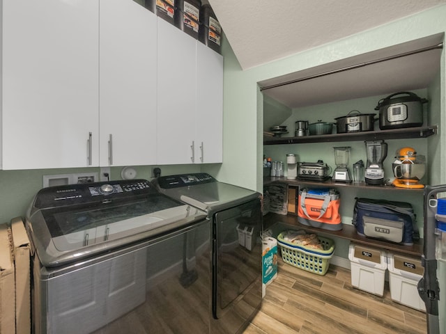 laundry area with washer and dryer, a textured ceiling, and light hardwood / wood-style floors