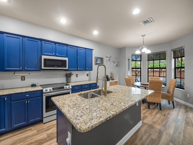 kitchen with a kitchen island with sink, blue cabinets, sink, hanging light fixtures, and electric range