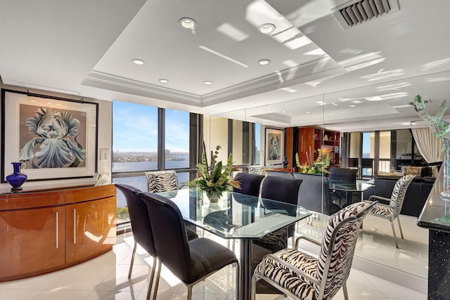 tiled dining room with a tray ceiling, a wall of windows, crown molding, and a water view