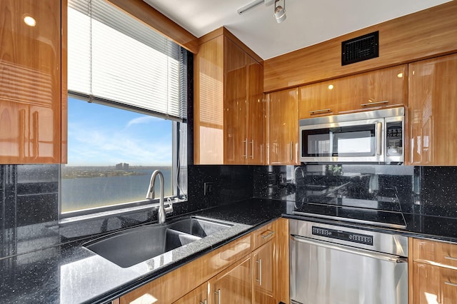 kitchen featuring sink, dark stone countertops, stainless steel appliances, and tasteful backsplash