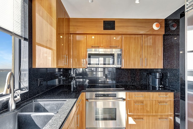 kitchen featuring tasteful backsplash, dark stone countertops, sink, and appliances with stainless steel finishes