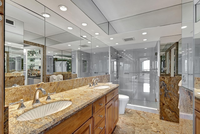 bathroom featuring vanity, a shower with shower door, and toilet