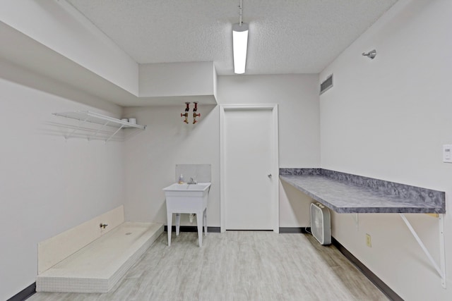 clothes washing area with wood-type flooring and a textured ceiling