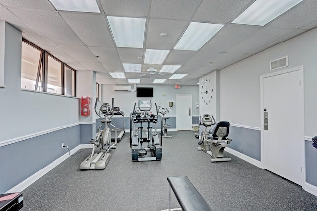 workout area with a drop ceiling, ceiling fan, and an AC wall unit