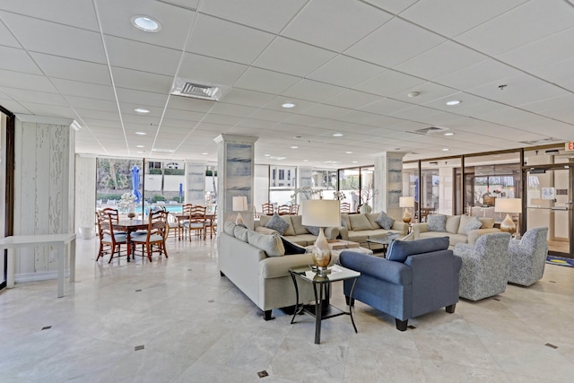 living room featuring a drop ceiling and a wall of windows