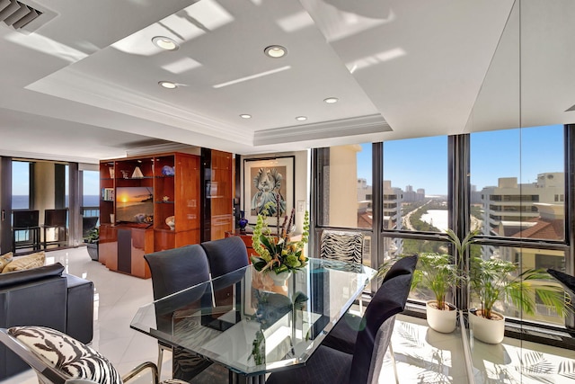 dining room with light tile patterned floors, a tray ceiling, a wall of windows, and crown molding