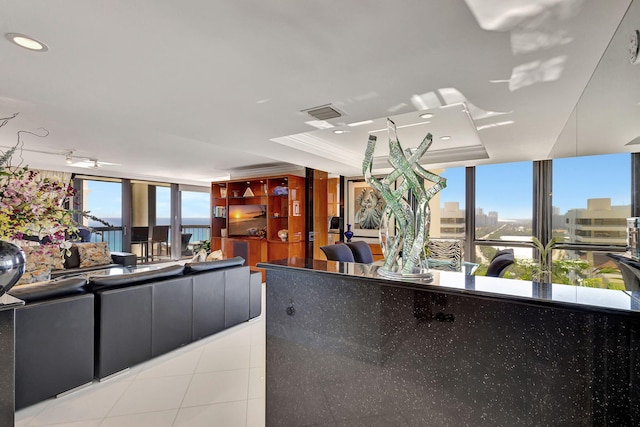 living room featuring floor to ceiling windows, light tile patterned floors, a raised ceiling, crown molding, and a water view