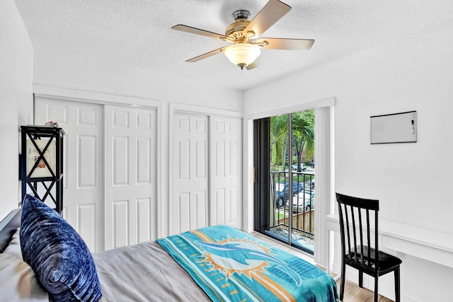 bedroom with ceiling fan, access to exterior, a textured ceiling, and two closets