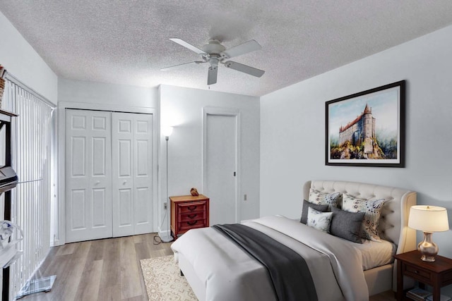 bedroom with ceiling fan, light hardwood / wood-style flooring, a textured ceiling, and a closet