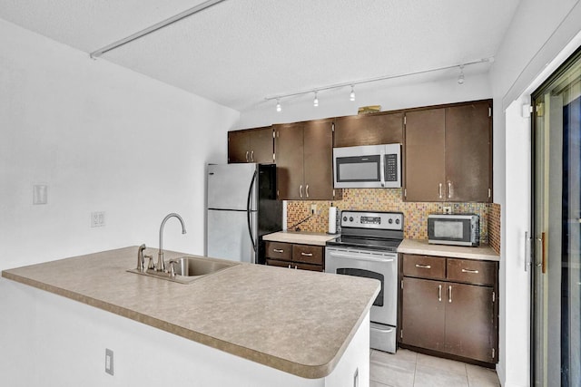 kitchen with decorative backsplash, kitchen peninsula, sink, and appliances with stainless steel finishes