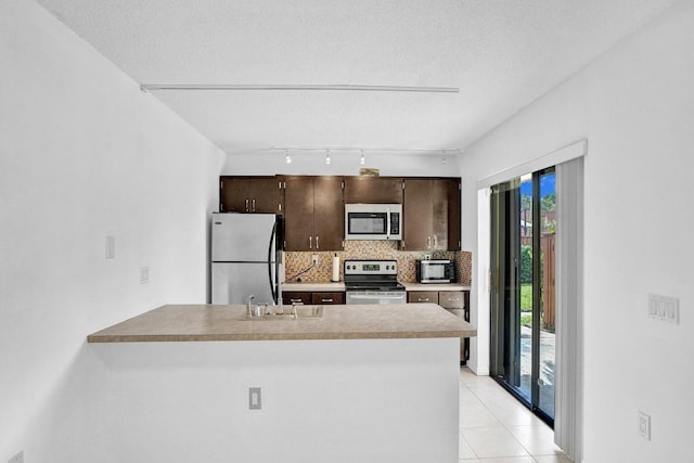 kitchen with kitchen peninsula, backsplash, a textured ceiling, stainless steel appliances, and sink