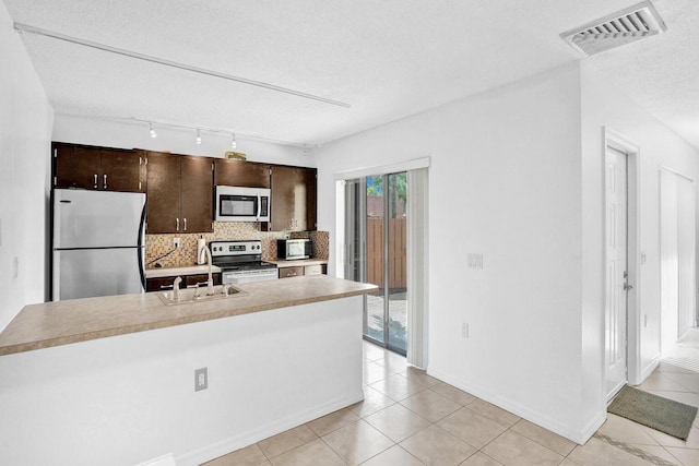 kitchen with sink, decorative backsplash, a textured ceiling, appliances with stainless steel finishes, and dark brown cabinetry