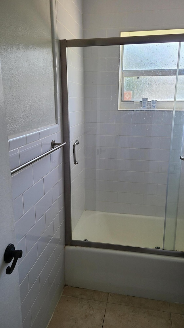 bathroom with combined bath / shower with glass door, tile patterned floors, and tile walls