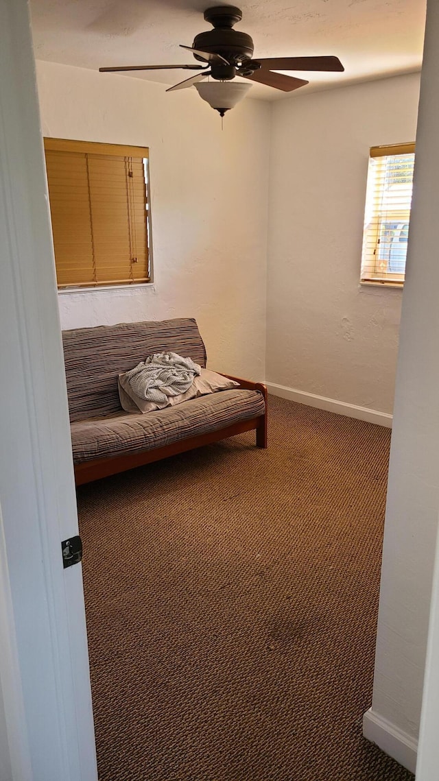 sitting room with ceiling fan and dark carpet