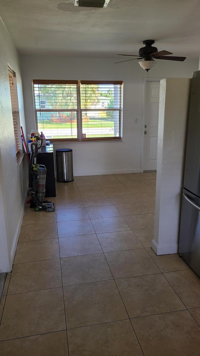 interior space featuring a wealth of natural light, ceiling fan, light tile patterned floors, and stainless steel refrigerator