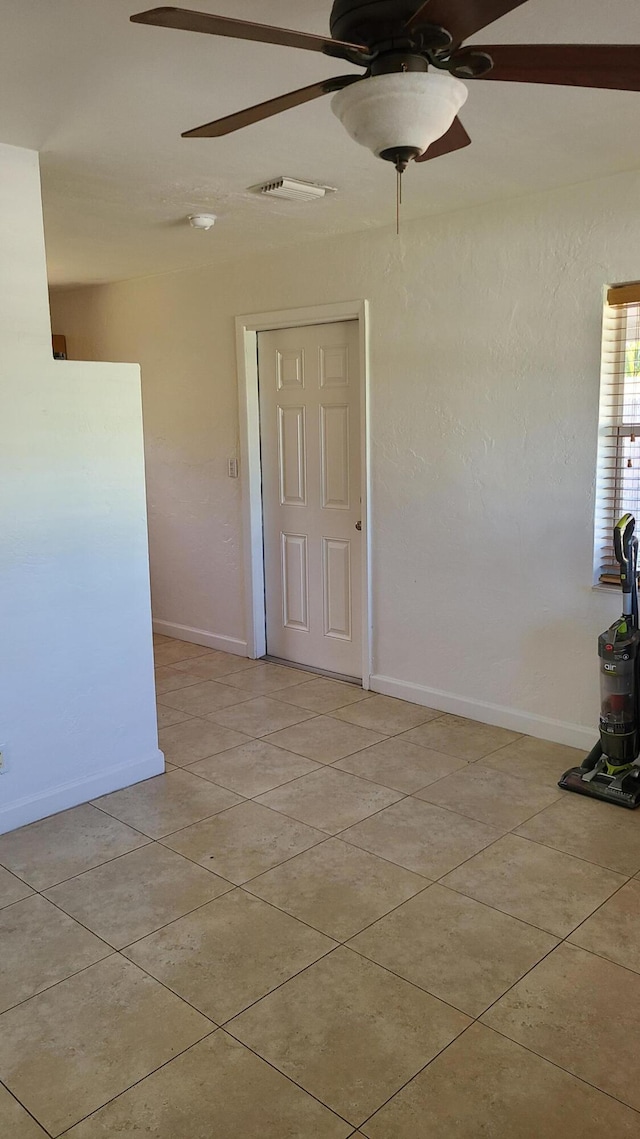 empty room featuring ceiling fan and light tile patterned floors