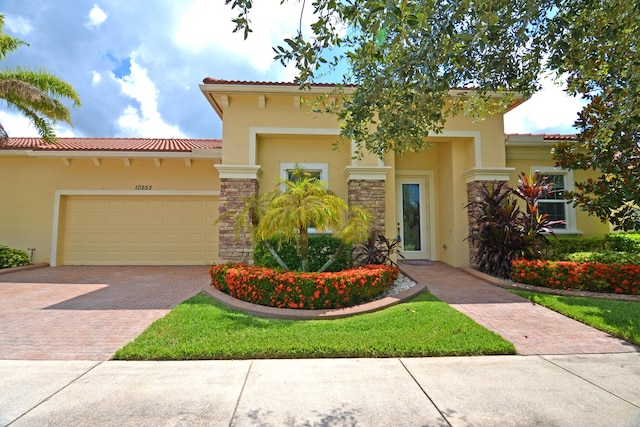 view of front of home featuring stucco siding, stone siding, a garage, and decorative driveway