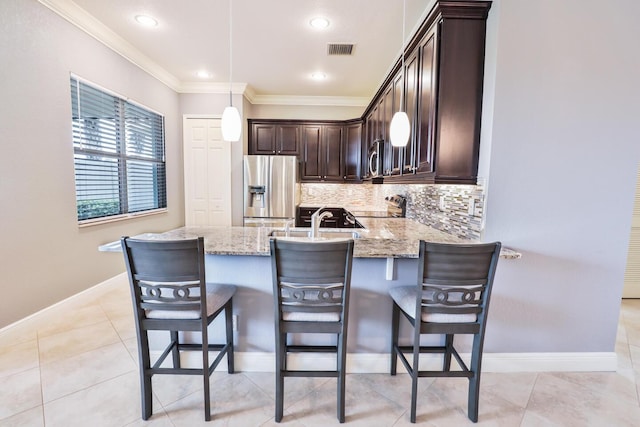 kitchen with light stone counters, tasteful backsplash, decorative light fixtures, appliances with stainless steel finishes, and kitchen peninsula