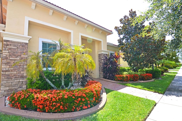 property entrance with stucco siding, stone siding, and an attached garage